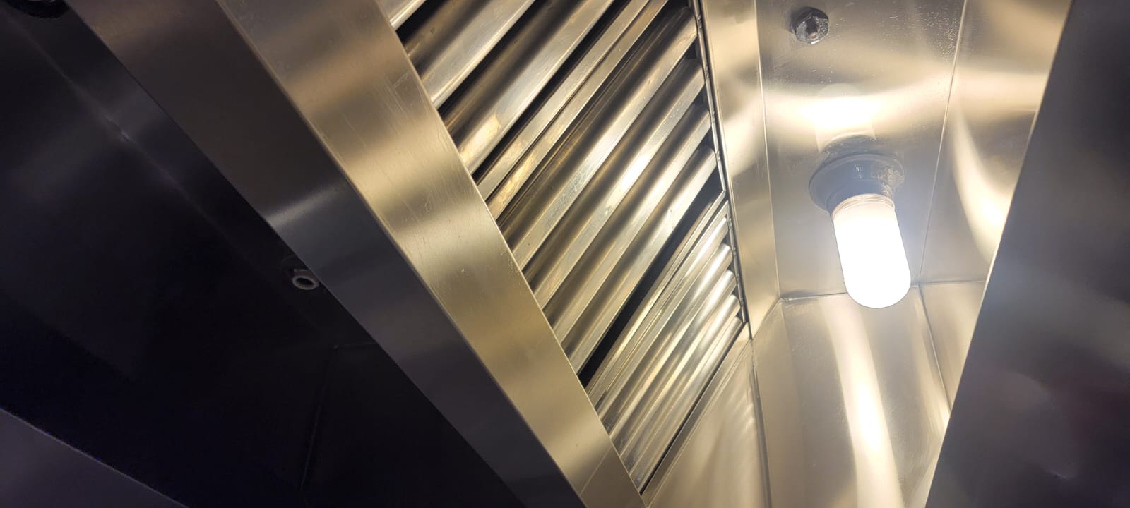 Chef cooking on a restaurant range beneath an exhaust hood