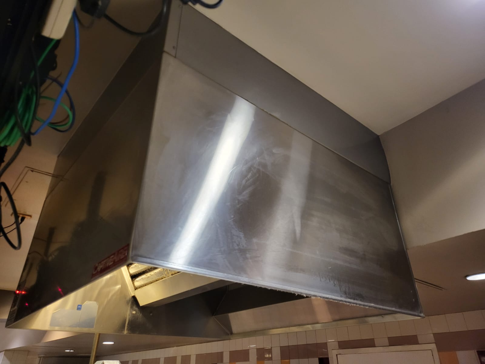 Chef cooking on a restaurant range beneath an exhaust hood